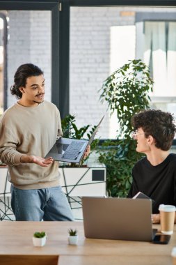 Team lead discussing project details with attentive colleague in a workspace, men in their 20s clipart