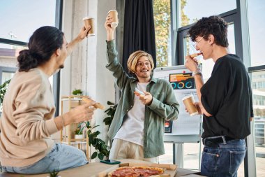 Genç erkekler, arkadaşça ve rahat bir atmosferde kahve ve pizzayla kadeh kaldırıyor.