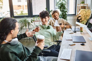 Kahve molası sırasında birlikte gülümseyen genç profesyoneller bir başlangıç ofisinde, post prodüksiyon ekibi