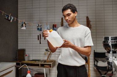 Genç Afrikalı Amerikalı fotoğrafçı, karanlık odada kimyasal çözelti tutuyor. Analog film geliştirme.