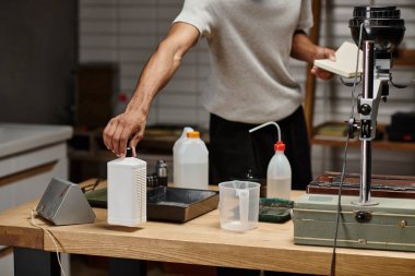 cropped african american photographer taking chemical solution in bottle, film development clipart