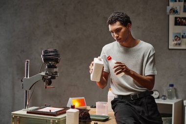 Koyu tenli fotoğrafçı film geliştirme çözümünü karanlık odada hazırlıyor, analog fotoğrafçılık