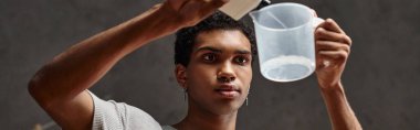 Yakışıklı Afro-Amerikan adam kimyasal çözeltiyi ölçü kabına döküyor, film geliştirme bayrağı.