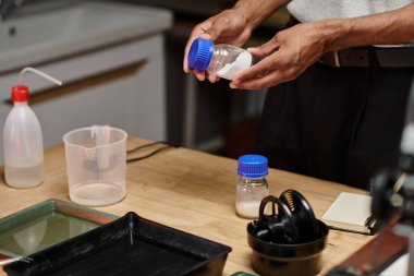 cropped african american photographer examines film developing powder in a modern analog darkroom clipart