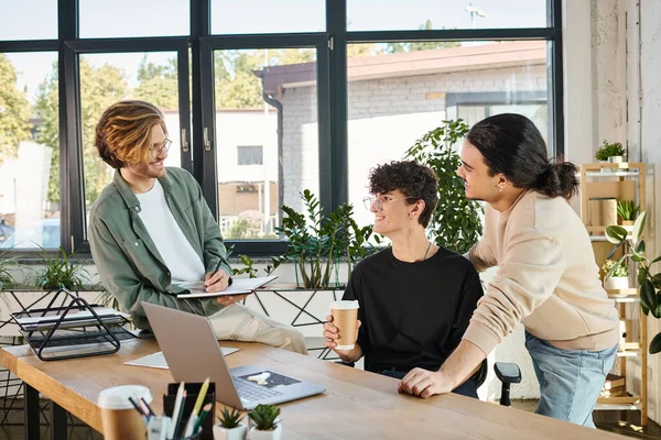 stock image happy young man with coffee to go discussing startup project with his male colleagues, teamwork