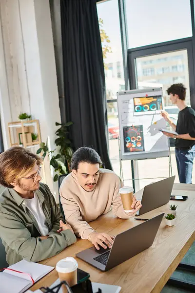 Stock image smart startup team members discussing project and working on laptops in coworking space, men in 20s