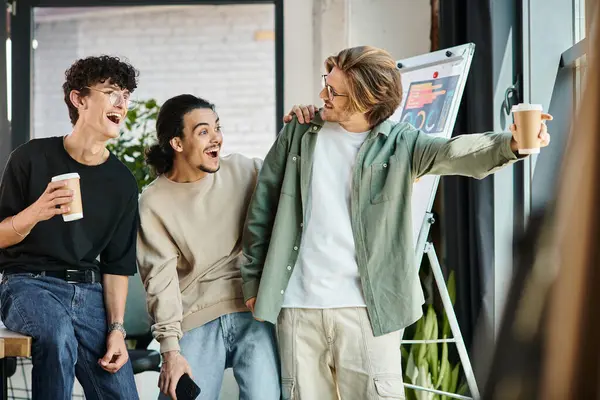 stock image young man in 20s showing something to excited startup team and looking away in a bright future