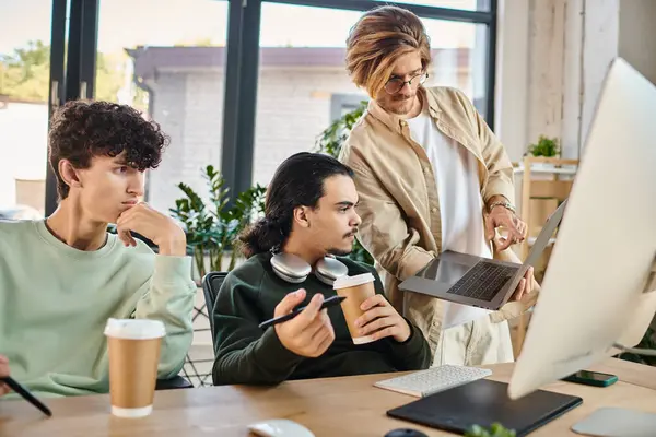 stock image post production team of young men focused on a retouching project on laptop in a well-lit office