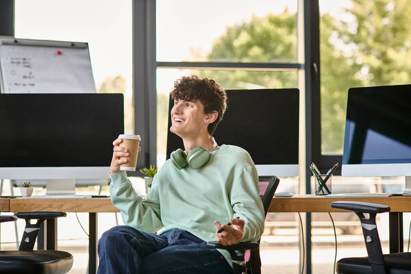 happy young man with headphones sitting in office chair and holding coffee, post production