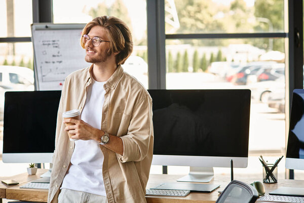 Smiling man with glasses holding coffee in modern office setup, post production team retoucher