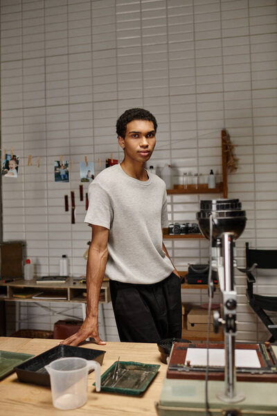 молодой афроамериканец, занимающийся искусством разработки фильмов в фотолаборатории с включенным светом