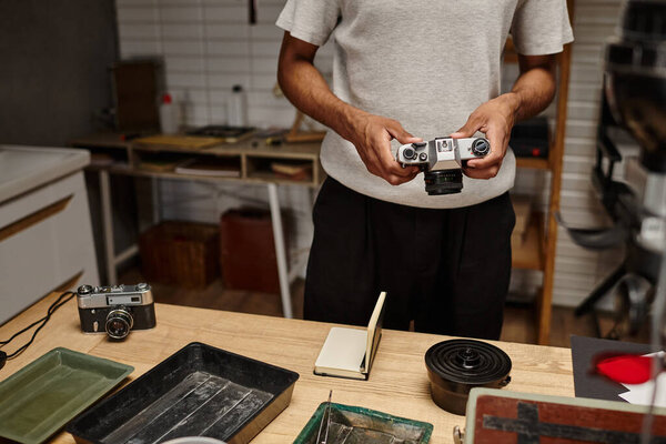 cropped view of african american photographer expertly handling a vintage camera in photo lab