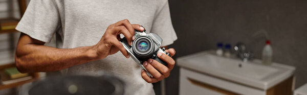 cropped view of african american photographer expertly handling a vintage camera, banner