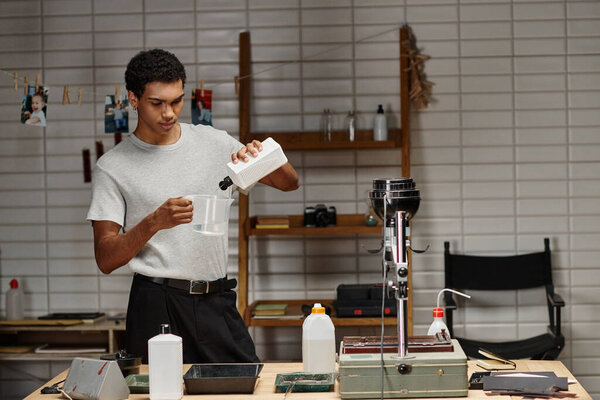 Афроамериканский фотограф смешивает химические растворы для аналоговой киноиндустрии