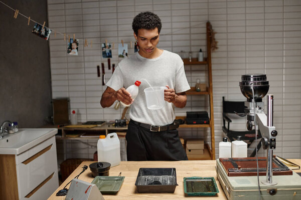 молодой африканский американский фотограф, занимающийся аналоговой киноразработкой в профессиональной темной комнате