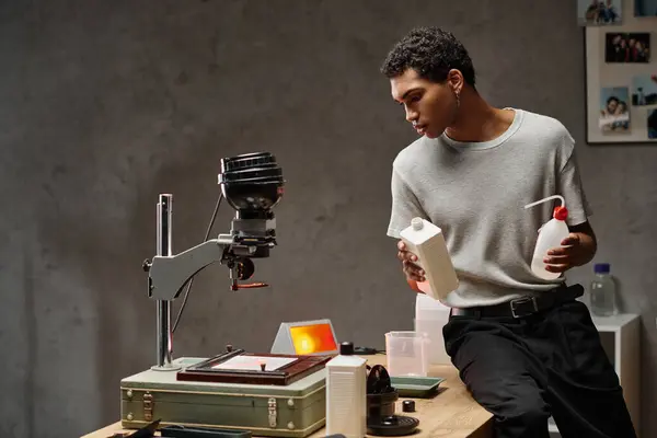 stock image A focused african american man carefully measuring photo chemicals in a well-organized darkroom