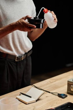 Afrikalı Amerikalı fotoğrafçının film geliştirme tankına kimyasal solüsyon dökerken çekilmiş bir fotoğrafı.