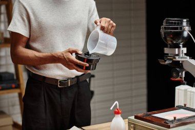 Afrikalı Amerikalı fotoğrafçının film geliştirme tankına kimyasal solüsyon dökerken çekilmiş bir fotoğrafı.