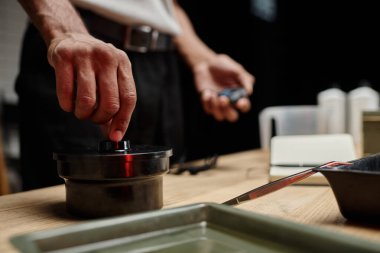 african american photographer securing a film canister lid in a darkroom, blurred timer in hand clipart