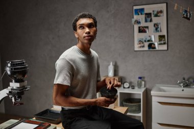 Yakışıklı genç Afrikalı Amerikalı fotoğrafçı karanlık bir odada film kapağını koruyor.