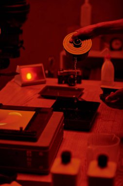 Fotoğrafçının kırpılmış görüntüsü film işleme için geliştirme sıvısı, kırmızı karanlık oda