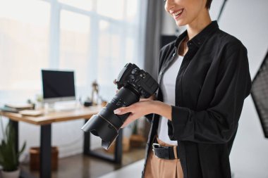 Stüdyoda çeşitli ekipmanlarla çalışan günlük giysiler içindeki genç kadın fotoğrafçı görüntüsü.