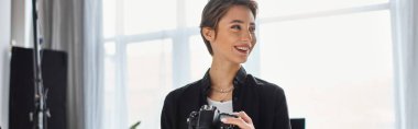 happy female photographer in casual clothes with camera in hands smiling and looking away, banner clipart