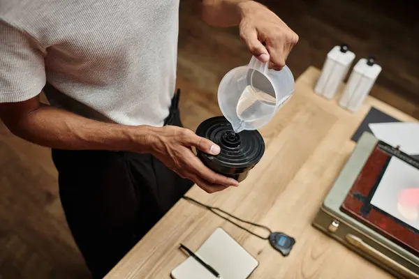 Afrikalı Amerikalı fotoğrafçının film geliştirme tankına kimyasal solüsyon dökerken çekilmiş görüntüsü.