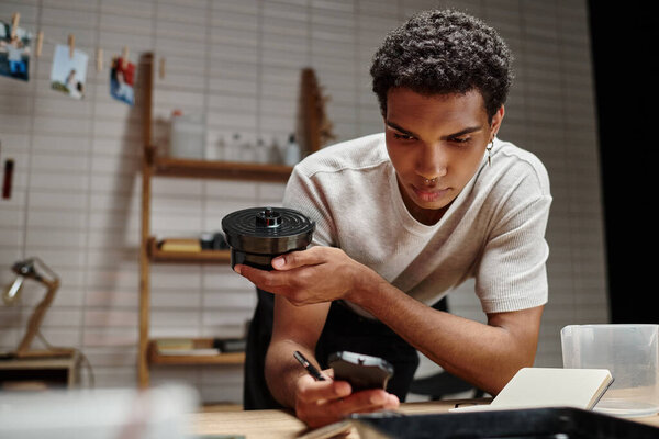 разработка аналоговой пленки, темнокожий человек тщательно умножает процесс в темной комнате