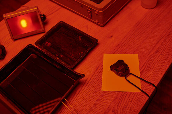 Искусство аналоговой фотографии, снятое в темной комнате с красным светом, с акцентом на инструменты разработки пленки