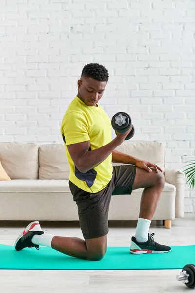 年轻的非洲裔美国人 穿着时髦的运动服 在家里接受哑铃式的健身垫训练 — 图库照片
