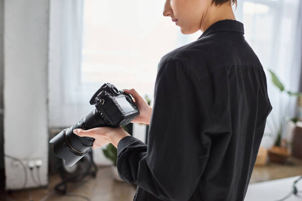 cropped view of female photographer in everyday attire working at studio with various equipment