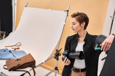 Güzel esmer kadın fotoğrafçı günlük kıyafetleriyle stüdyoda çalışıyor.