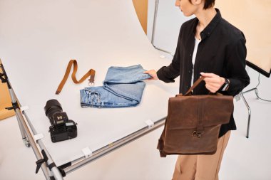 Çekici genç bayan fotoğrafçı kot pantolon ve kahverengi sırt çantasının fotoğraflarını çekmeye hazırlanıyor.