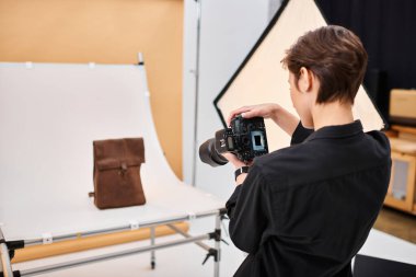 Çekici yetenekli kadın fotoğrafçı stüdyosunda kahverengi derili sırt çantasının fotoğraflarını çekiyor.