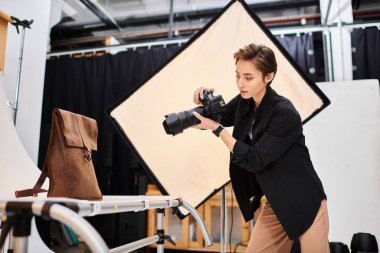 Güzel bir bayan fotoğrafçı stüdyosunda kahverengi derili sırt çantasının fotoğraflarını çekiyor.