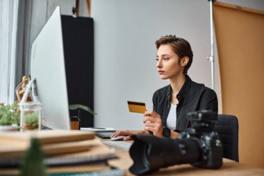 Rahat giyimli güzel bayan fotoğrafçı kredi kartıyla internetten ödeme yapıyor.