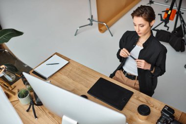 good looking short haired female designer in casual attire working on her project on drawing tablet clipart