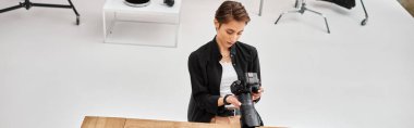 Modern fotoğraf makinesi ve afiş taşıyan sıradan giyinmiş düşünceli genç profesyonel kadın fotoğrafçı.