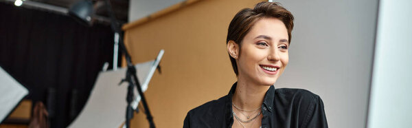 молодая привлекательная веселая женщина с аксессуарами счастливо улыбается в своей фотостудии, баннер