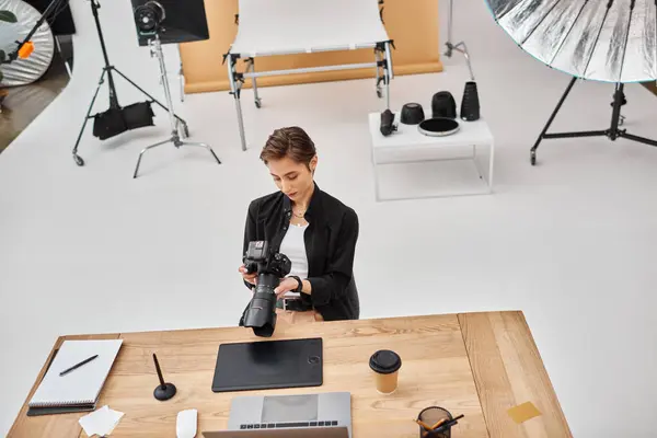 Çekici profesyonel kadın fotoğrafçı günlük kıyafetlerle stüdyoda kamerasıyla çalışıyor.