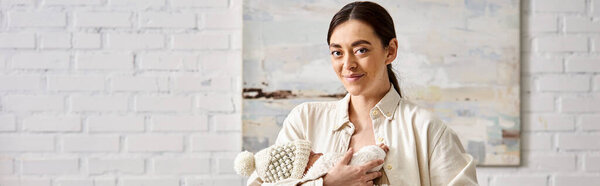 cheerful mother in homewear holding lovingly her newborn baby boy, modern parenting, banner