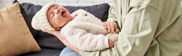 loving mother in casual homewear holding carefully her adorable newborn baby boy, modern parenting