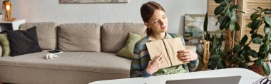 banner of pensive teenage girl holding book while studying from home, thinking about future clipart