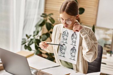 Genç kız evde e-öğrenim resim dersi için anatomi çizimlerini analiz ediyor, dizüstü bilgisayarına bakıyor.
