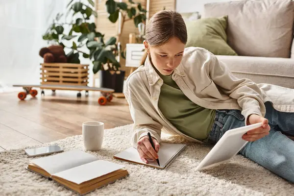 stock image teenage girl holding tablet and taking notes while making her homework, digital native concept