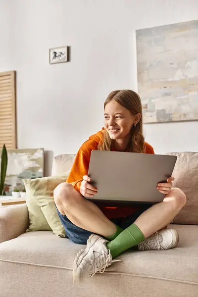 stock image cheerful teenager girl with a laptop enjoying her time and sitting on the sofa in living room