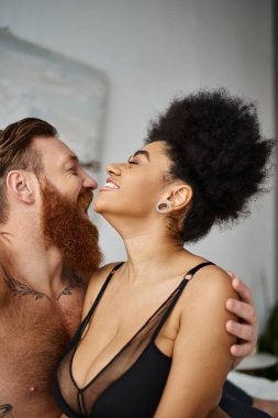 Mutlu dövmeli adam sütyenli Afrikalı Amerikalı kız arkadaşı kucaklıyor, çok kültürlü seksi çift.