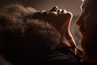 Afro-Amerikan kadın portresi kıvırcık saçlı kızıl saçlı sakallı adamı baştan çıkaran seksi çift.