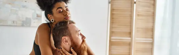 banner of diverse couple, african american woman embracing her tattooed man in bright room